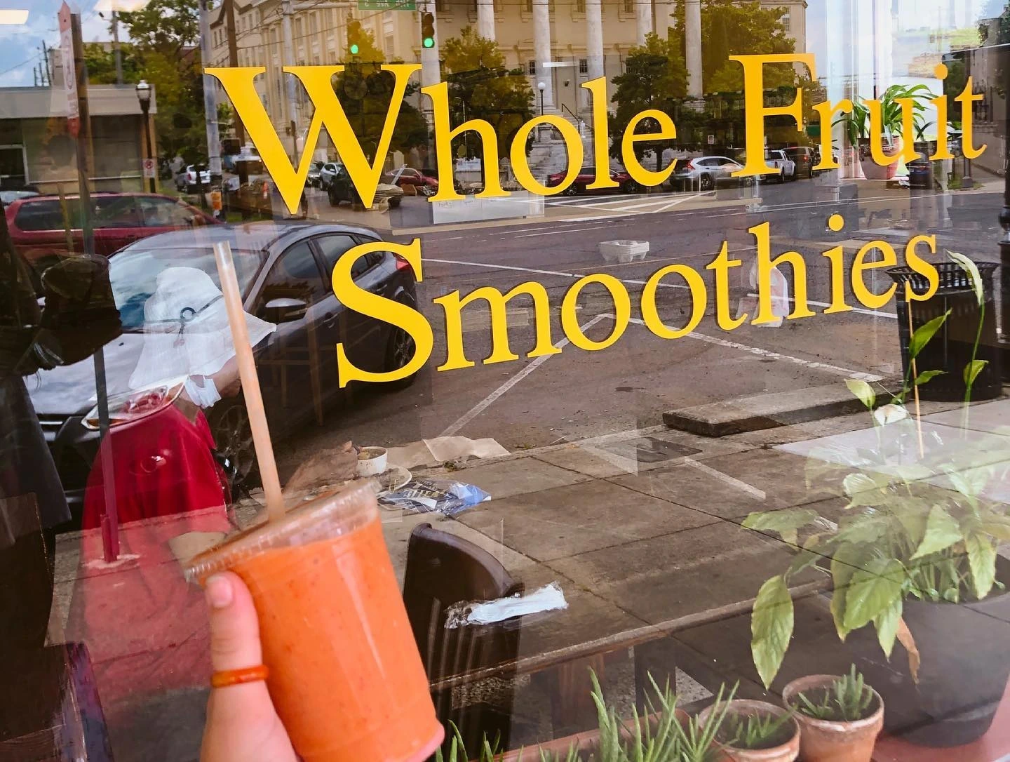 Whole Fruit Smoothies sign with a hand holding a pink smoothie up in front